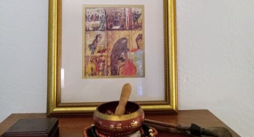 A framed old world artwork with a bowl and a wooden stick inside of it. A stone etched with the word "Faith".